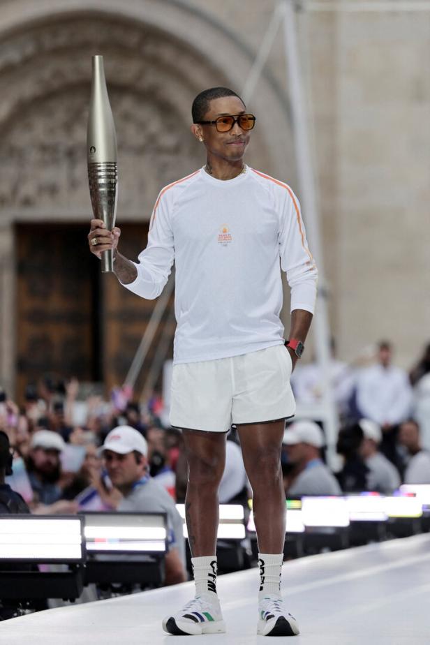 Pharrell Williams trägt die olympische Fackel.