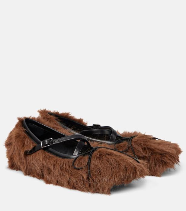 Ein Paar braune, fellartige Ballerinas mit schwarzen Riemen und Schnürsenkeln.