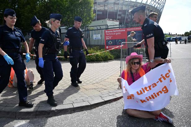Polizisten führen eine Demonstrantin mit einem Protestplakat ab.