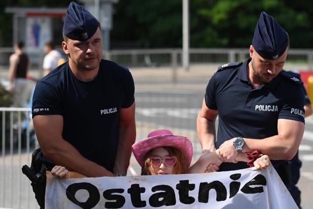 Polizisten führen eine Demonstrantin mit einem Transparent ab.