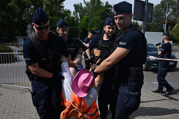 Polizisten tragen eine Demonstrantin mit einem rosa Hut weg.