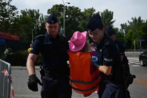 Polizisten führen eine Demonstrantin mit einem rosa Hut ab.
