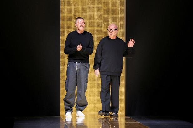 Zwei Männer stehen vor einem goldenen Hintergrund.