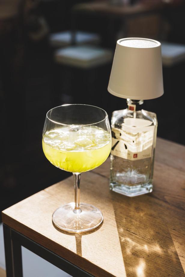 Ein Matcha-Gin-Tonic in einem Weinglas auf einem Tisch.