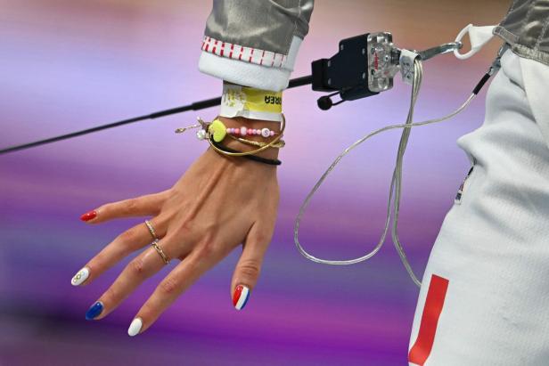 Die Hand einer Fechterin mit Nagellack in den Farben der französischen Flagge und den olympischen Ringen.