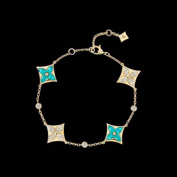 Ein goldenes Armband mit türkisfarbenen und diamantbesetzten Blütenmotiven auf schwarzem Hintergrund.