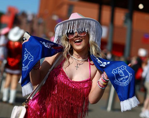 Eine lachende Frau mit einem Schal des FC Everton und einem pinkfarbenen Paillettenkleid.