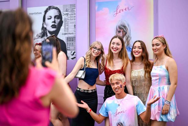 Fans posieren vor Postern von Taylor Swift, darunter „Reputation“ und „Lover“.