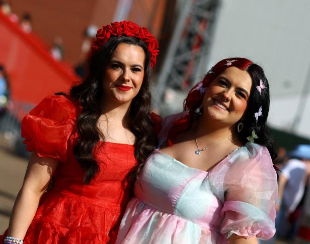 Zwei Frauen posieren in farbenfrohen Kleidern und mit Blumenschmuck im Haar.