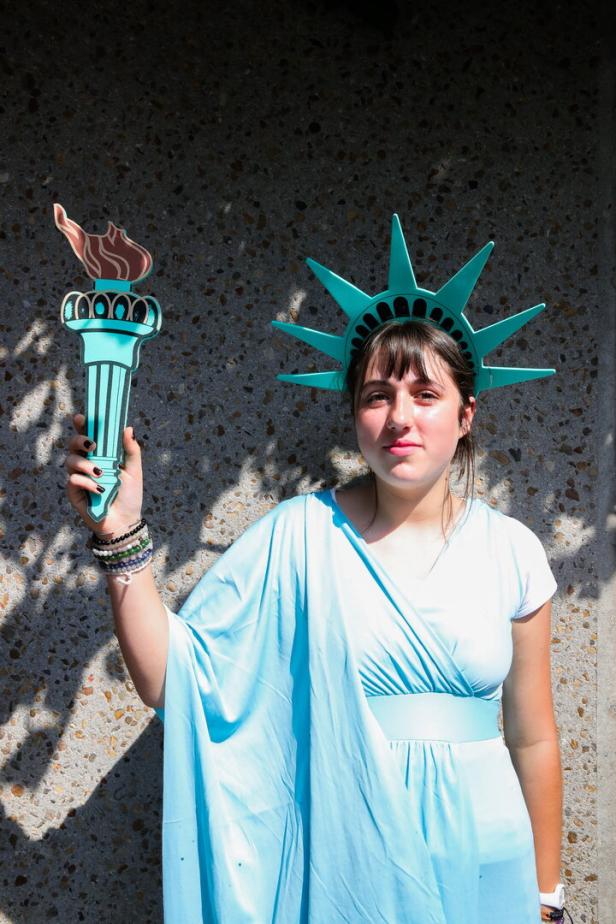 Eine junge Frau, als Freiheitsstatue verkleidet, hält eine Fackel in der Hand.