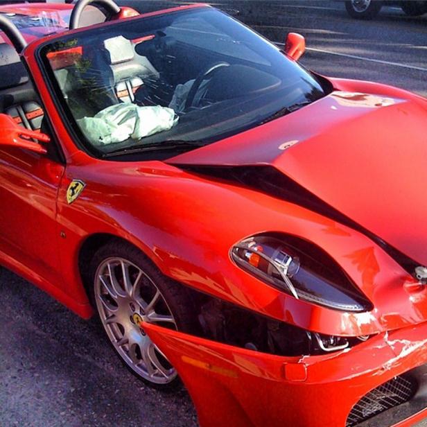 Ein roter Ferrari Spider mit ausgelöstem Airbag und beschädigter Karosserie.