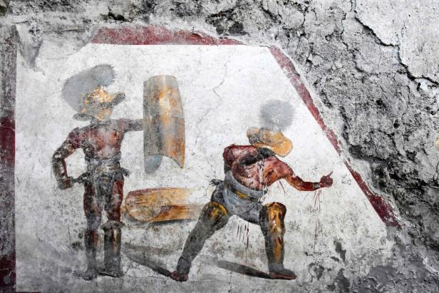 Eine Wandmalerei zeigt zwei Gladiatoren im Kampf.