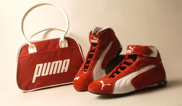 Eine rote Puma-Tasche und zwei rote Puma-Rennschuhe stehen auf einem Tisch.