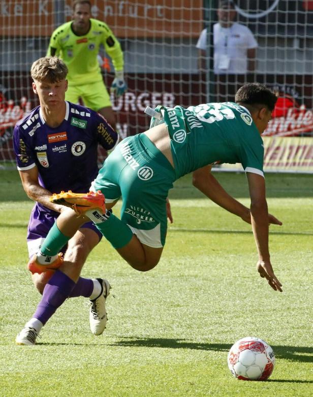 Zwei Fußballspieler kämpfen um den Ball auf dem Spielfeld.