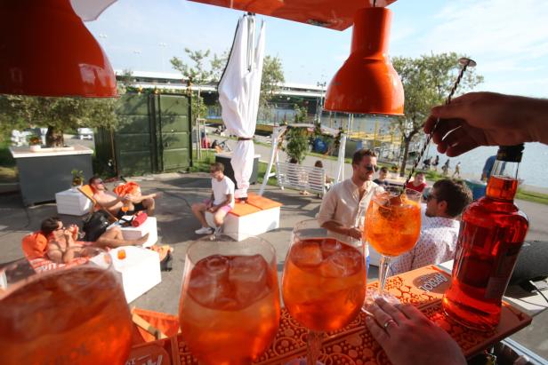 Menschen entspannen sich bei Aperol Spritz an einer Bar im Freien.