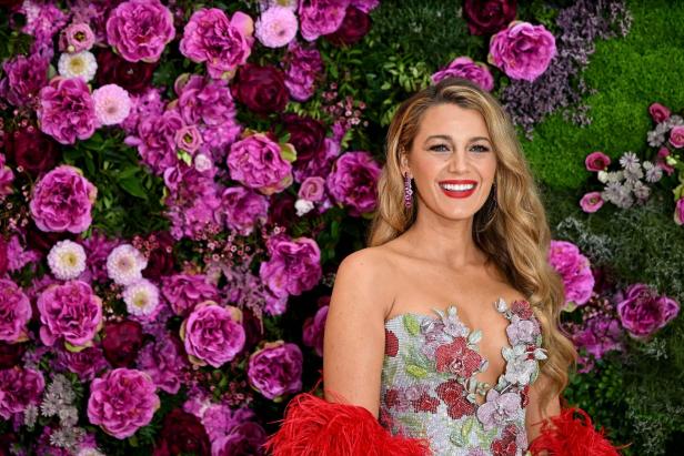 Blake Lively posiert vor einer Wand aus Blumen.