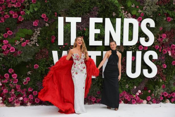 Blake Lively und eine weitere Frau posieren vor einer Blumenwand für „It Ends With Us“.