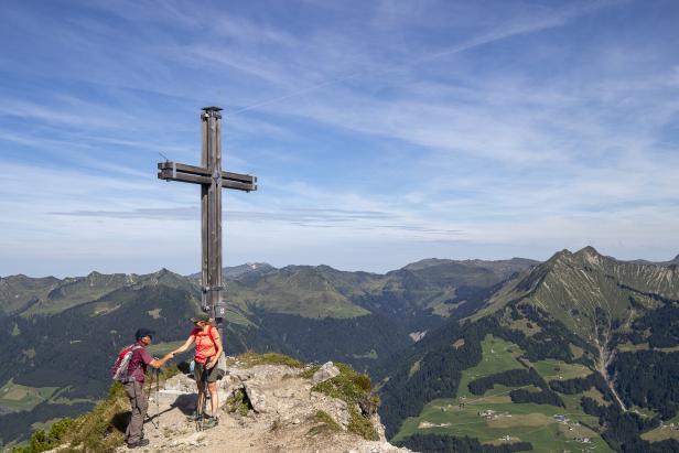 Gipfel der Kellaspitze im großen Walsertal in Vorarlberg mit Gipfelkreuz und zwei Bergsteigern