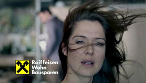 Eine Frau mit wehendem Haar, im Vordergrund das Logo von Raiffeisen Wohn Bausparen.