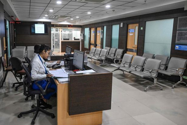 In einem Wartezimmer einer Apotheke sitzen zwei Angestellte an einem Schreibtisch.