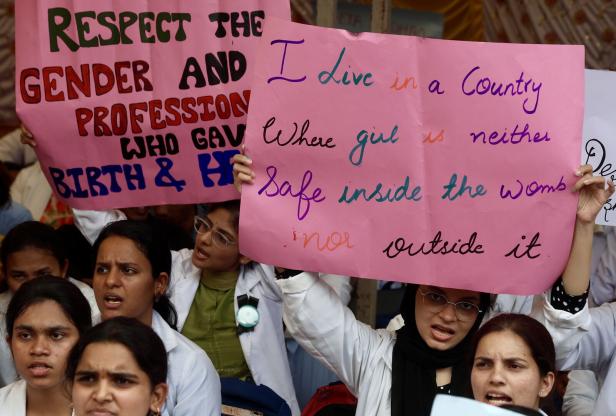 Demonstrantinnen halten Schilder mit Aufschriften über Geschlechtergerechtigkeit hoch.