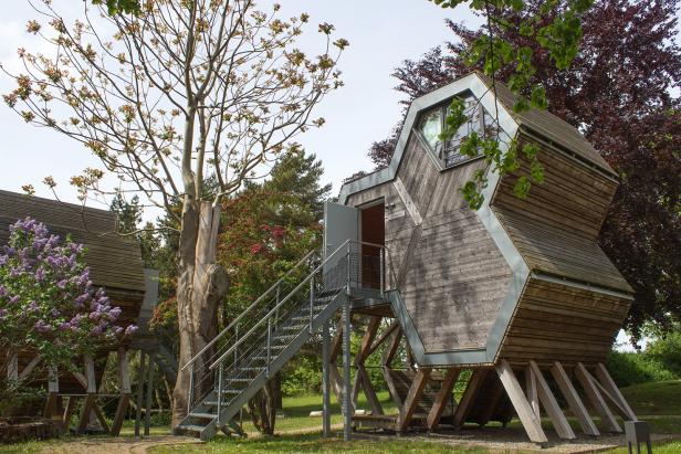 Ein ungewöhnliches Holzhaus auf Stelzen mit einer Treppe zum Eingang.