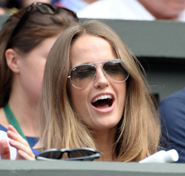 Eine Frau mit Sonnenbrille jubelt bei einer Sportveranstaltung.