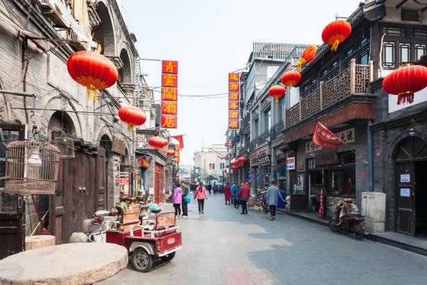 Eine belebte Straße in Peking ist mit roten Laternen geschmückt.