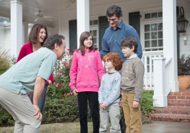 Eine Familie steht vor ihrem Haus.