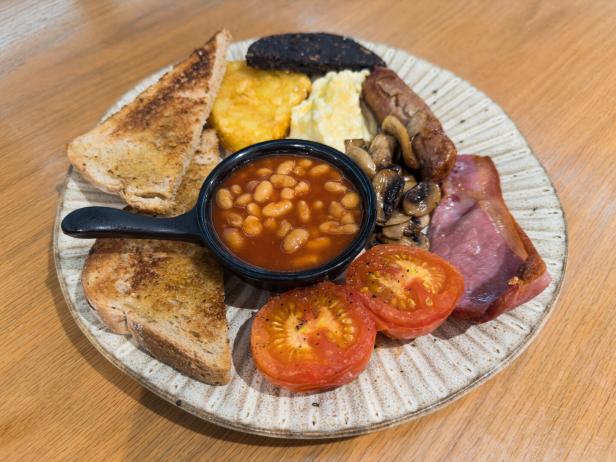 Ein Teller mit einem traditionellen englischen Frühstück mit Speck, Wurst, Bohnen und Toast.