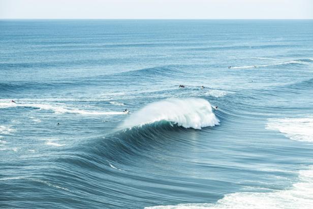 Ein Surfer reitet auf einer riesigen Welle im offenen Meer.