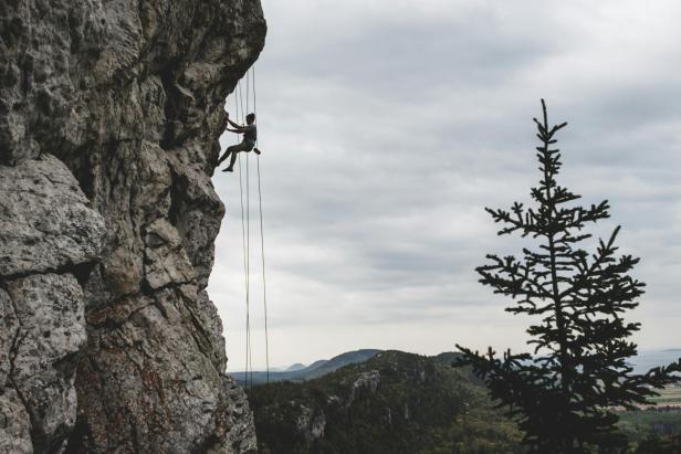 Ein Mann klettert an einer Felswand in den Alpen.