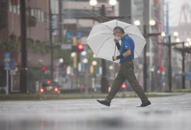 A passerby holding an umbrella walks in heavy rains caused by Typhoon Shanshan in Kagoshima