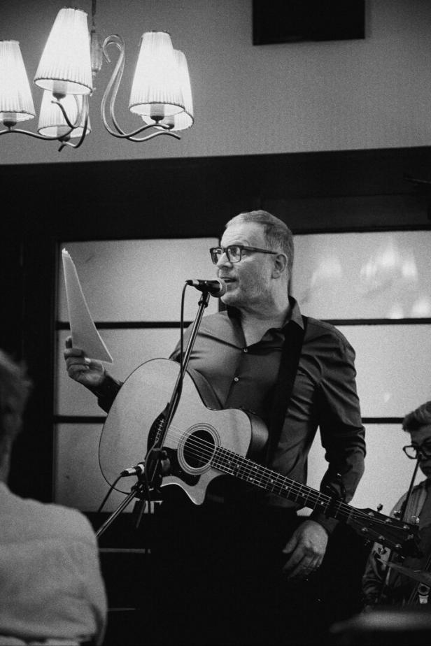Bernhard Moshammer spielt Gitarre und singt in einem Lokal.