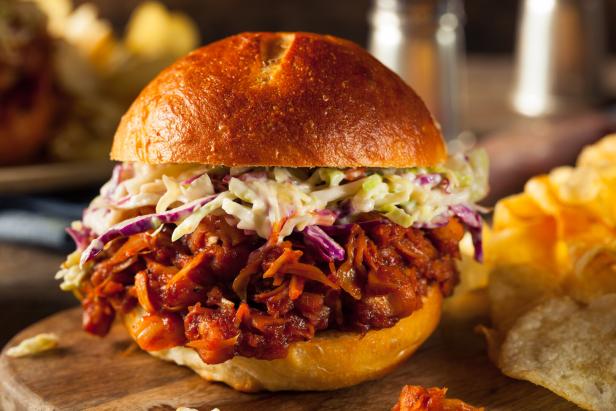 Ein Pulled Jackfruit Burger mit Krautsalat auf einem Holztisch.