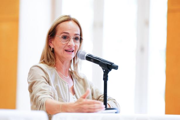 Eine Frau mit Brille spricht bei einer Veranstaltung in ein Mikrofon.