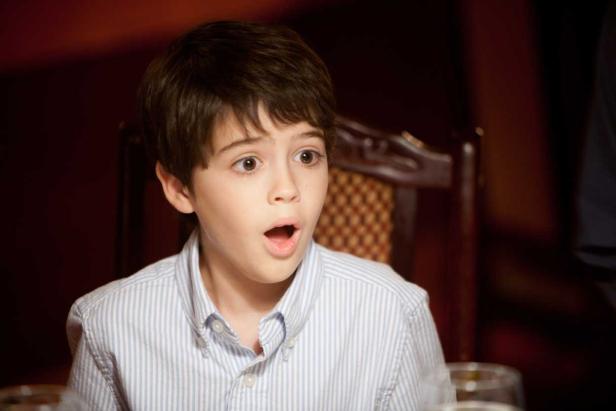 Ein Junge mit offenem Mund und überraschtem Gesichtsausdruck sitzt am Tisch.