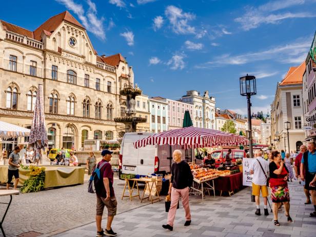 Ein belebter Marktplatz in Steyr, Österreich, mit Menschen und Verkaufsständen.