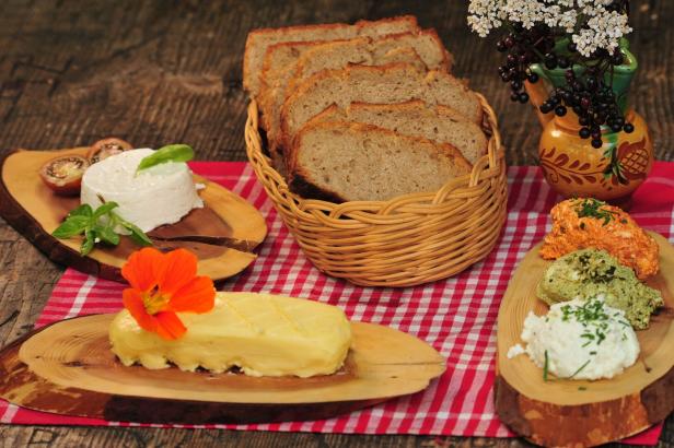 Brot, Butter, Frischkäse und verschiedene Aufstriche auf einem rot-weiß karierten Tuch.