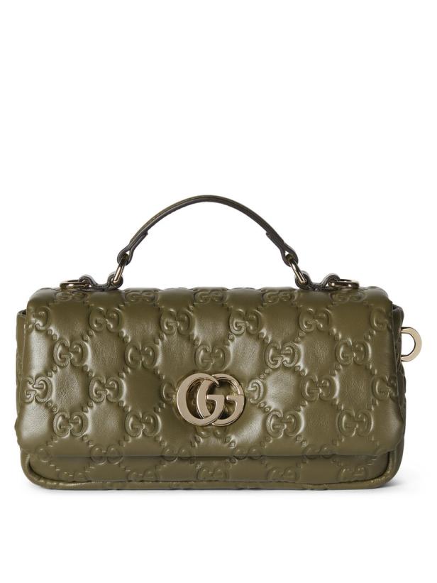 Eine olivgrüne Gucci-Tasche mit goldenem GG-Logo und geprägtem Muster.