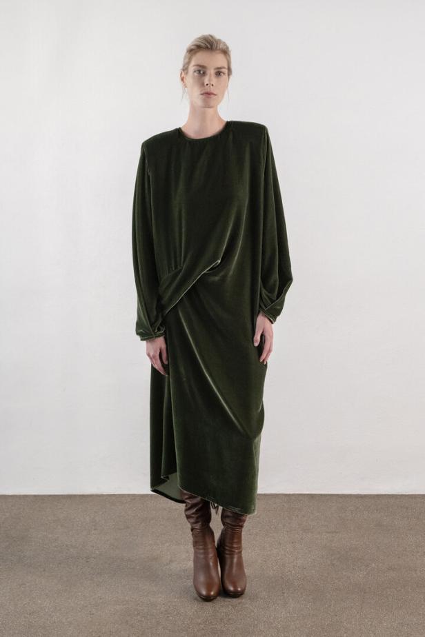 Eine Frau trägt ein grünes Samtkleid und braune Stiefel.