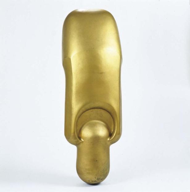 Eine goldene, abstrakte Skulptur auf einem weißen Hintergrund.