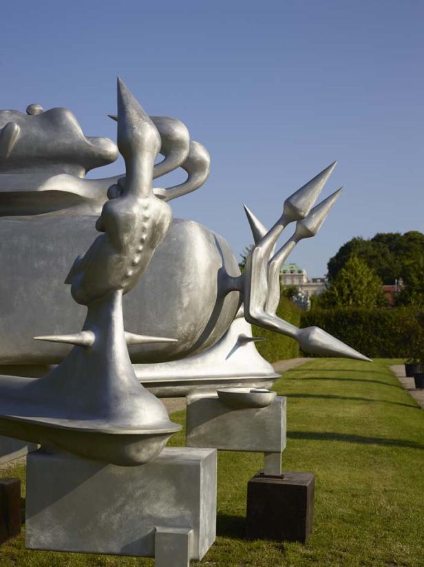 Eine silberne Skulptur steht in einem Park auf einem Rasen.