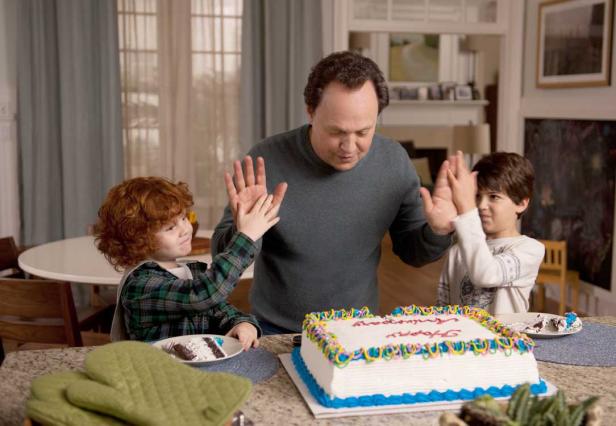 Ein Mann und zwei Kinder feiern mit einer Torte, indem sie sich gegenseitig abklatschen.