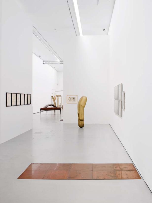 Eine Kunstausstellung mit verschiedenen Skulpturen und Gemälden in einem hellen Raum.