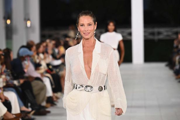 Christy Turlington auf dem Laufsteg in einem weißen Blazer und Gürtel.