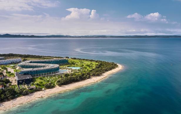 Luftaufnahme eines Resorts mit Strand und türkisfarbenem Wasser.
