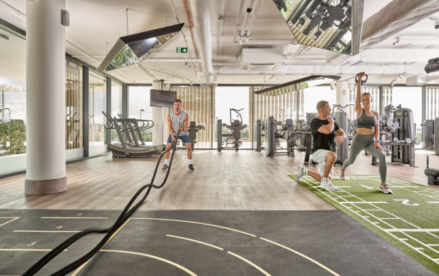In einem Fitnessstudio trainieren Menschen mit Seilen und Gewichten.