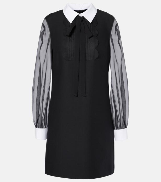 Ein schwarzes Minikleid mit weißem Kragen, Schleife und transparenten Ärmeln.