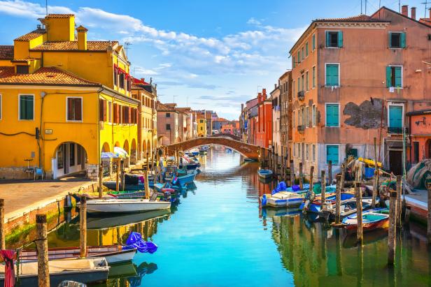 Ein Kanal in Chioggia, gesäumt von bunten Häusern und kleinen Booten.